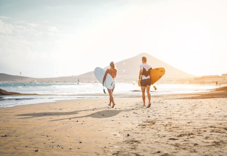 Happy surfers running with surfboards on the beach